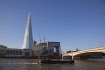 England, London, Southwark southbank, Barge passing under London Bridge with the Shard skyscraper designed by Renzo Piano in the city's London Bridge Quarter.