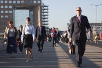 England, London, Early morning commuters crossing London Bridge towards the City Financial district.