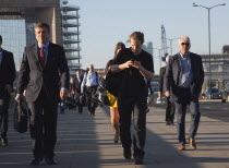 England, London, Early morning commuters crossing London Bridge towards the City Financial district.