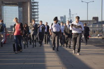 England, London, Early morning commuters crossing London Bridge towards the City Financial district.