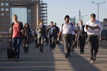 England, London, Early morning commuters crossing London Bridge towards the City Financial district.