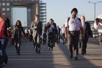 England, London, Early morning commuters crossing London Bridge towards the City Financial district.