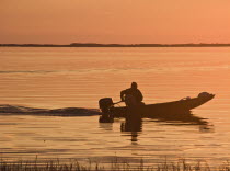 USA, Florida, Fisherman in his motorboat at Sunset.