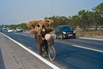 Vietnam, Woman on Bicycle in north region with a load of brooms.