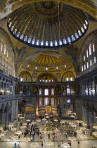 Turkey, Istanbul, Sultanahmet, Haghia Sophia Sighseeing tourists beneath the dome with murals and chandeliers in the Nave of the Cathedral.