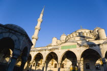 Turkey, Istanbul, Sultanahmet Camii, The Blue Mosque domes seen from the Courtyard with Arabic text from the Koran in green and the Absolution Fountain in the foreground.