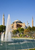 Turkey, Istanbul, Sultanahmet, Haghia Sophia with dome and minarets beyond the water fountain in the gardens with sightseeing tourists.