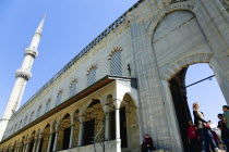 Turkey, Istanbul, Sultanahmet Camii, The Blue Mosque exterior wall of the Courtyard with minaret and visiting sightseeing tourist.