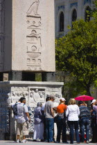 Turkey, Istanbul, Sultanahmet, Tourists in the Roman Hippodrome in At Meydani beside Egyptian Obelisk with Hieroglyphics from Luxor and relief at base showing Theodosius I and courtiers.