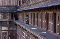 India, Uttar Pradesh, Agra, Taj Mahal, two young men standing on open balcony of red and cream painted building.