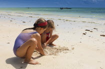 Zanzibar, Paje, Two young girls playing in the hot sunshine of the sandy beach.