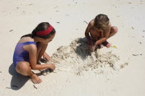 Zanzibar, Paje, Two young girls playing in the hot sunshine of the sandy beach.