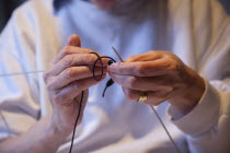 Woman hand knitting wool together with needles.