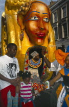 England, London, Notting Hill Carnival, Man and young girl in front of golden coloured float.