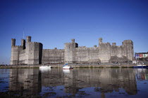 Wales, Gwynedd, Caernarfon Castle Against Deep Blue Sky, Overlooking The River Seiont as the tide comes in, Construction Started In 1283, And Prince Charles Held His Investiture At The Castle In 1969....