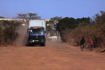 Gambia, heavy goods vehicle carrying sea container on unsurfaced red dirt road to terminal on the Bund Road. 