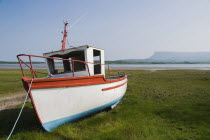 Ireland, County Sligo, Rosses Point, Boat moored on the 3rd beach with Ben Bulben in the background.