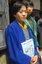 Bhutan, Mongar, Portrait of a Bhutanese school girl holding Social Studies textbook.