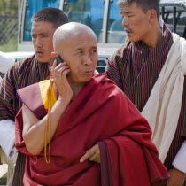 Bhutan, Red robed Tibetan Buddhist monk talking on his mobile phone.
