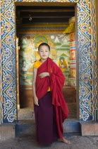 Bhutan, Chimi Lakhang, Boy monk standing in doorway.