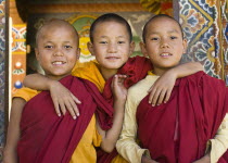 Three young boy monks standing in doorway of temple in Punakha, Bhutan.