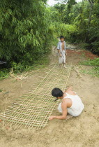 Bangladesh, Chittagong Hills, Khagrachari, Two men weaving a large bamboo fence panel.