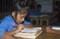 Bangladesh, Chittagong, Rowangchhari Upazila, Mro minority ethnic group children sat in primary school classroom with teaching aids on walls around them provided by development programme.