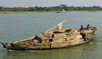 Bangladesh, Boat heavily laden with cargo of timber and furniture on river.