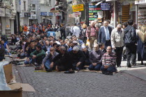 Turkey, Istanbul, Fatih, Sultanahmet, Men sat in street in readiness for midday prayers.