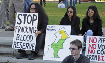 Canada, Alberta, Lethbridge, Three Blood Tribe members holding protest signs at anti-fracking demonstration. Map of Blood Reserve showing oil company concessions to Bowood Energy Ltd and Murphy Oil Co...
