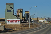 Canada, Alberta, Milk River, Old wooden grain silos or elevators still in use, Large sign announcing Family Doctors Needed for this small town near the USA border.