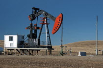 Canada, Alberta, Milk River Ridge, Oil pump jack or nodding donkey on the edge of the Baaken play, Flare tower at right.