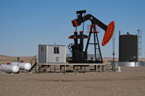 Canada, Alberta, Milk River Ridge, Oil pump jack or nodding donkeyand storage tank on the edge of the Baaken play near the Montana, USA border.