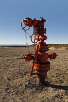 Canada, Alberta, Del Bonita, Christmas tree atop a capped off oil well on the edge of the Baaken play with line of the Rocky Mountains on the horizon.