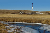 Canada, Alberta, Del Bonita, Fracking near a water source for tight shale oil and gas on the edge of the Bakken play. Ensign Energy of Calgary drilling rig, water storage tanks and road tanker. The wa...