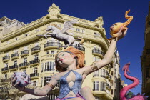 Spain, Valencia Province, Valencia, Female Papier Mache figure with a horse on her head  in the street during Las Fallas festival.