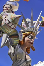 Spain, Valencia Province, Valencia, Papier Mache figure of a woman resembling the Statue of Liberty with another figure flying around her during Las Fallas festival.