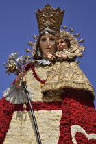 Spain, Valencia Province, Valencia, Statue of Virgen de los Desamparados, Our Lady of the Forsaken, decked out with flowers carried in the religious procession during Las Fallas festival.