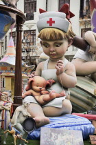 Spain, Valencia Province, Valencia, Papier Mache figure of young girl in nurses outfit with teddy bear in the street during Las Fallas festival.