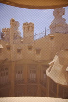 Spain, Catalonia, Barcelona, La Pedrera or Casa Mila on Passeig de Gracia, designed by Antoni Gaudi, view of the roof through mesh covered attic window.