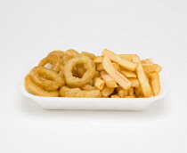 Food, Cooked, Seafood, fried squid rings and potato chips in an insulated polystyrene foam tray on a white background.