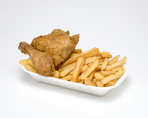 Food, Cooked, Poultry, Battered chicken breast fillet and drumstick with potato chips in a polystyrene foam tray on a white background.