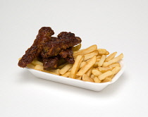 Food, Cooked, Meat, Sticky pork ribs with potato chips in a polystyrene foam tray on a white background.