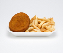 Food, Cooked, Fish, Two fishcakes with potato chips in a foam polystyrene tray on a white background.