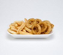 Food, Cooked, Vegetables, Battered onion rings with potato chips in a foam polystyrene tray on a white background.