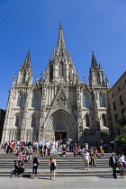 Spain, Catalonia, Barcelona, People on the steps below the main facade of the Gothic Cathedral in the Old Town district.