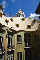 Spain, Catalonia, Barcelona, Tourist visitors on the roof of Casa Mila apartment building known as La Pedrera or Stone Quarry designed by Antoni Gaudi in the Eixample district.