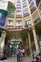 Spain, Catalonia, Barcelona, Tourist visitors in the central courtyard of Casa Mila apartment building known as La Pedrera or Stone Quarry designed by Antoni Gaudi in the Eixample district.