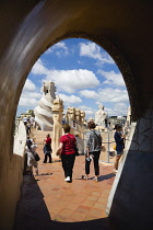 Spain, catalonia, Barcelona, Tourist visitors amongst the chimneys and vents on the roof of Casa Mila apartment building known as La Pedrera or Stone Quarry designed by Antoni Gaudi in the Eixample di...