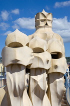 Spain, Catalonia, Barcelona, Chimneys and vents on the roof of Casa Mila apartment building known as La Pedrera or Stone Quarry designed by Antoni Gaudi in the Eixample district.